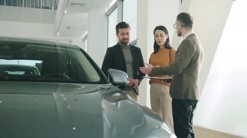 Cheerful Family Buying Car in Dealership Talking To Manager Looking at New Auto