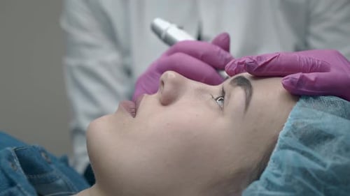 Kosmetikerin färbt junge Frauenaugenbraue in Schwarz Nahaufnahme