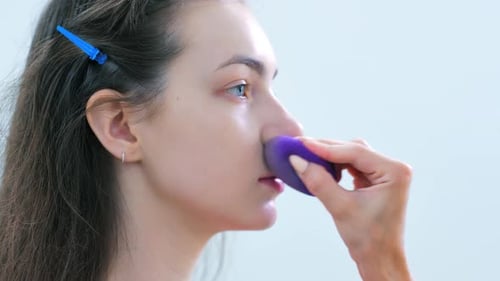 Woman Receiving Makeup Application with Purple Sponge