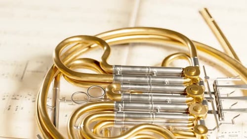French horn on the music note sheets. Elegant brass instrument. Orchestra. 4k HD