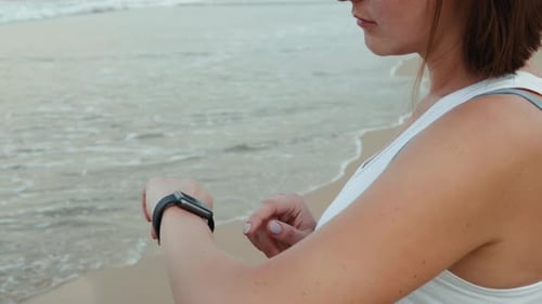 Woman Uses Smartwatch on Sandy Beach