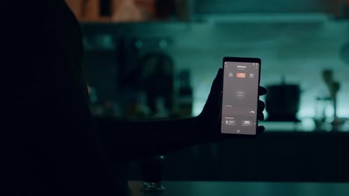 Man Holding Smartphone with Lighting Control Application Turning on the Lights