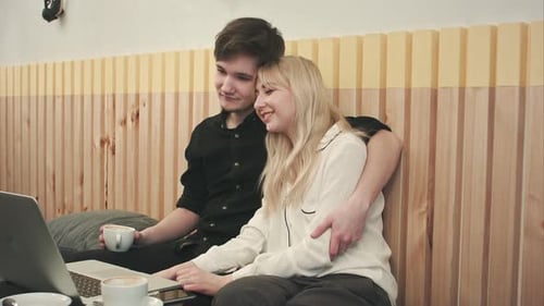 Hipster Couple on Vacation Sitting in Cafe Drinking Coffee Enjoying Time Together