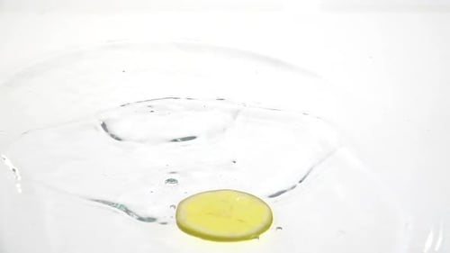 Lemon Slice Falls Into Clear Water in Close Up