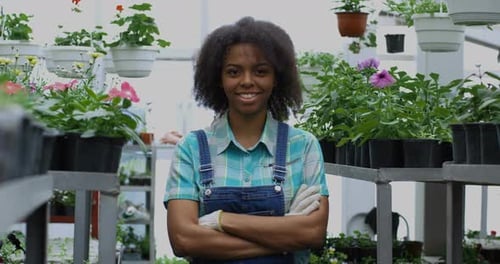 Smiling Woman in Greenhouse with Flowers
