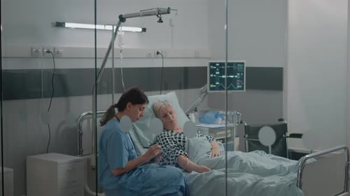 Medical Assistant Doing Checkup Visit for Patient in Hospital Ward Bed