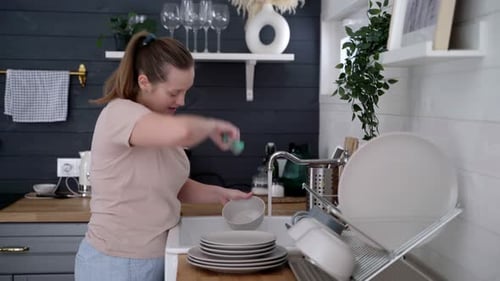 Woman Washing Dishes in Bright Kitchen Sink