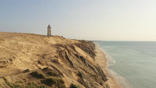 Lighthouse on Coastal Cliff above Blue Ocean