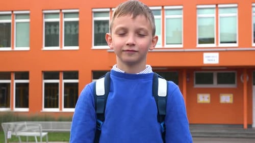 A Young Boy Celebrates - an Elementary School in the Background