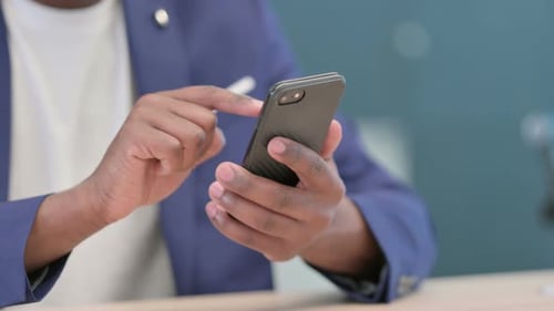 Nahaufnahme der Hände eines afrikanischen Geschäftsmannes mit Smartphone