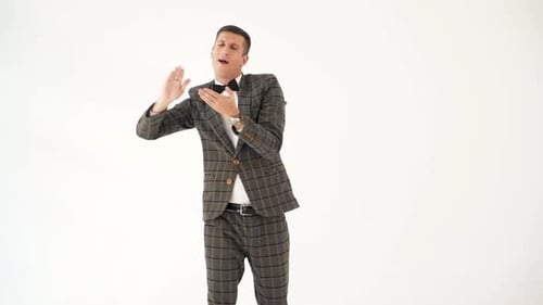 Un divertido hombre con un traje gris a cuadros muestra una escena con dinero