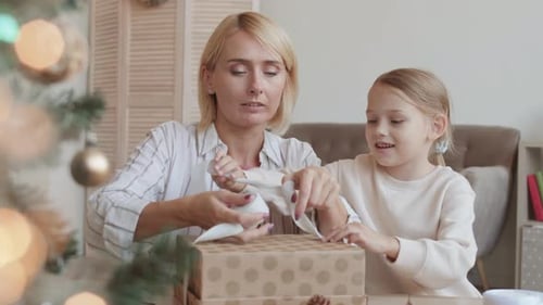 Woman and Child Unwrapping Christmas Gift Together
