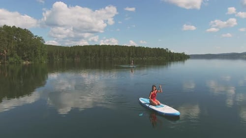 Women Paddle Boarding on Calm Lake