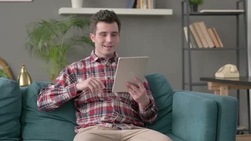 Young Adult on Tablet for Video Call on Sofa