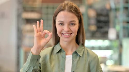 Young Woman Gives OK Hand Gesture Indoors