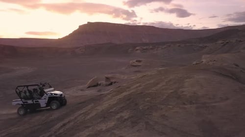Panning view of OHV driving over dirt hill in the desert