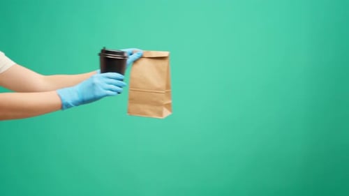 People's Hands Passing Each Other Packed Boxes with Food Delivery Against Mint Studio Background