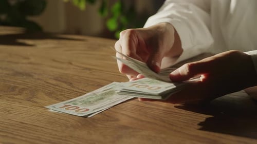 Handheld Close Up of Caucasian Woman Hands Counting Money in 100 Dollar Bills