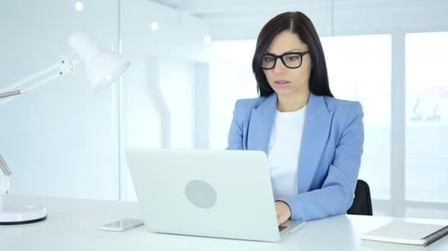 Focused Woman Working on Laptop in Bright Office