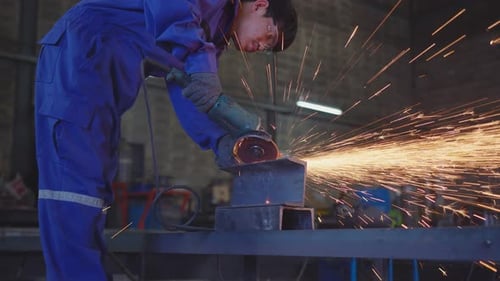 Worker Grinding Metal with Sparks in Workshop
