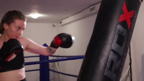 Female Boxer Punches Heavy Bag in Boxing Ring