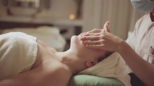 Young Beautiful Caucasian Woman Lying on Spa Bed Get Facial Massage Treatment with Aroma Essential