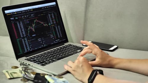 человек с ноутбуком и телефоном рассматривает экран с криптовалютой