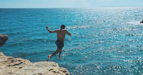 Mann springt von der Klippe ins Meer