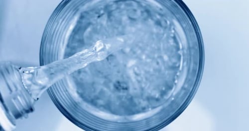 Frisches, reines Mineralwasser aus der Flasche in ein Glas gießen