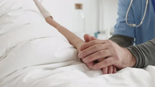 Doctor Holding Patient's Hand in Hospital Bed