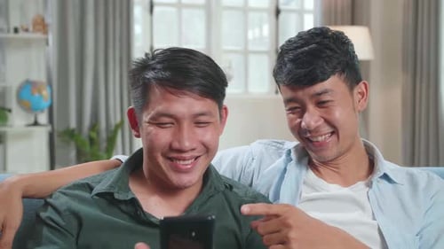 Two Young Adults Laughing Together at Mobile Phone