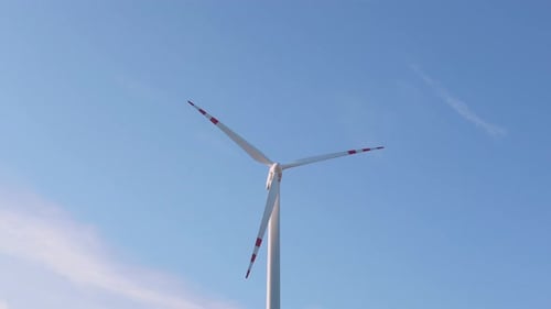 Close Up of a Wind Turbine Spinning on Light Blue Sky on Background