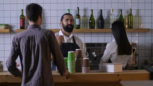 Male Barista Communicating with Client at Cafe