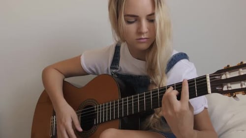 Blonde Woman Playing Acoustic Guitar Indoors