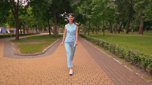 Woman Listening to Music and Walking in Park