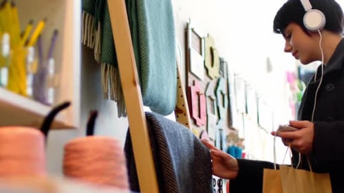 Woman Browsing Scarves in a Boutique with Headphones