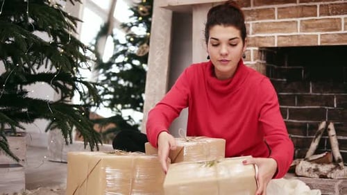 Woman Wrapping Christmas Presents by Christmas Tree
