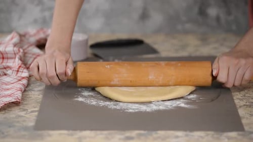 Hands Rolling Dough with Wooden Rolling Pin