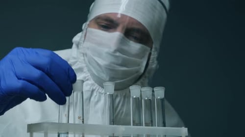 Scientist in Protective Kit Holding Test Tube with Reagent. Laboratory Glassware Containing Chemical