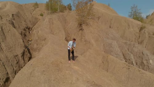 Barefoot Man Playing Saxophone on Sandy Hill