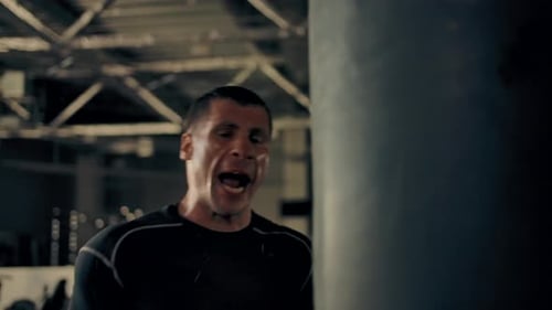 Man Training Boxing with Punching Bag at Gym