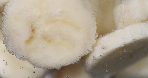 Sliced Bananas Submerged in Clear, Bubbly Liquid