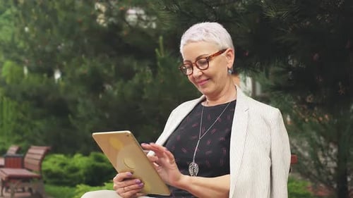 Senior Woman Using Tablet in Park