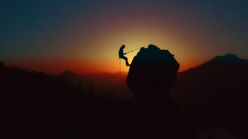 Climber Rappelling on Rock Face at Sunrise