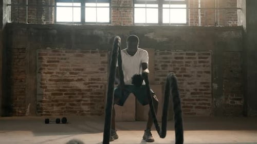 Rope workout. Sport man doing battle ropes exercise at gym