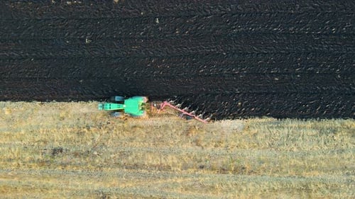 Aerial view of a tractor plowing agricultural farm field.
