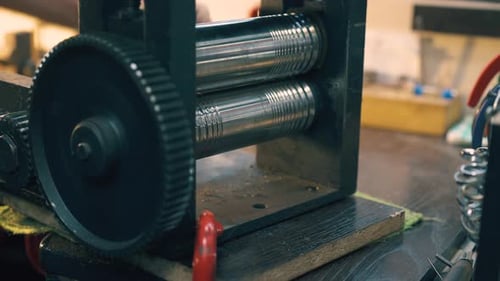 Craftsperson uses rolling mill machine in workshop