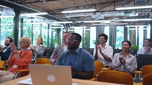 Conference Audience Applauds Presentation in Sunny Room