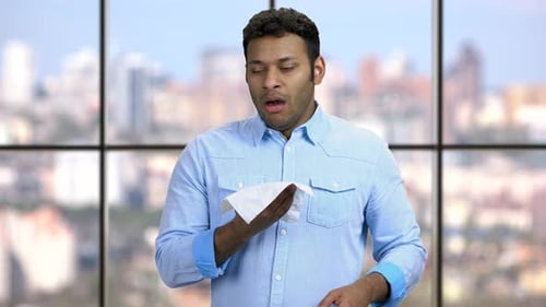 Young Man Sneeze in Tissue at Modern Workplace
