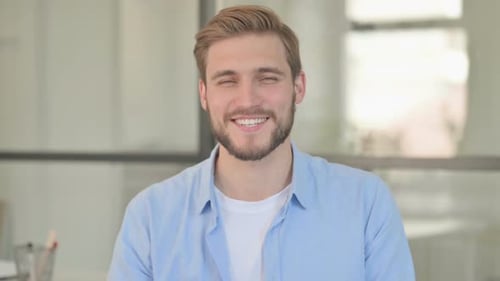 Man Smiling and Waving in Office Setting